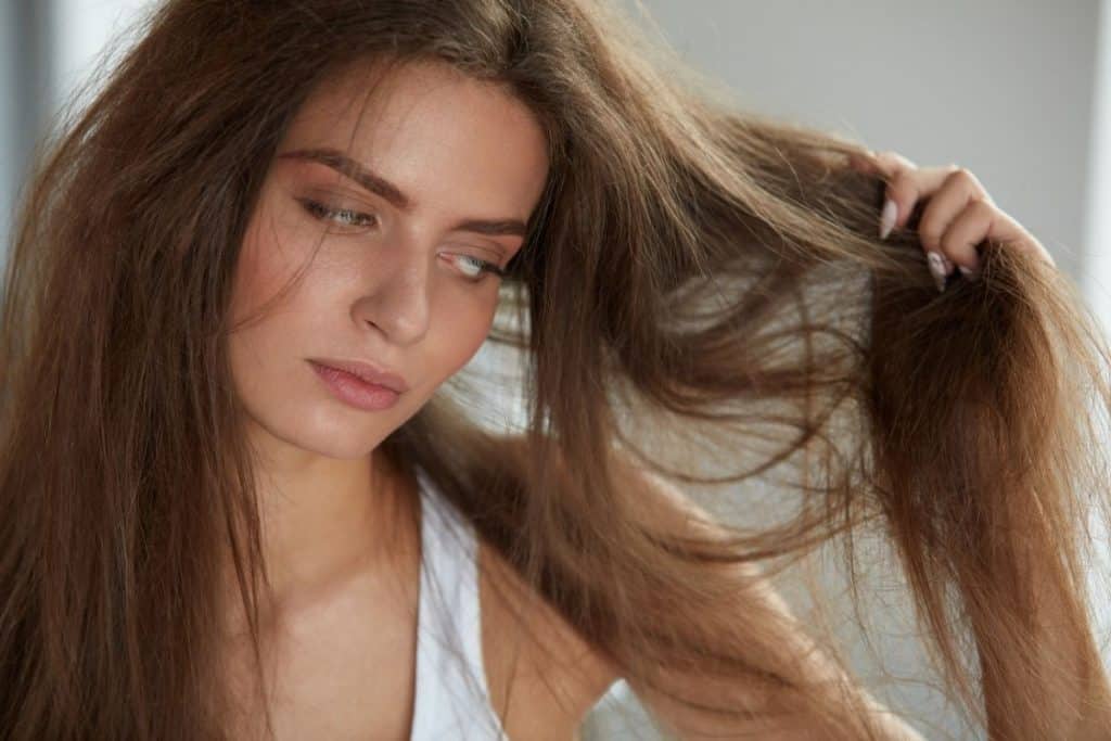 woman inspecting her long dry hair